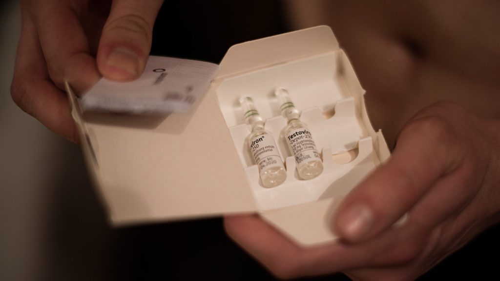 An up-close image of hands holding a white box filled with two small vials.